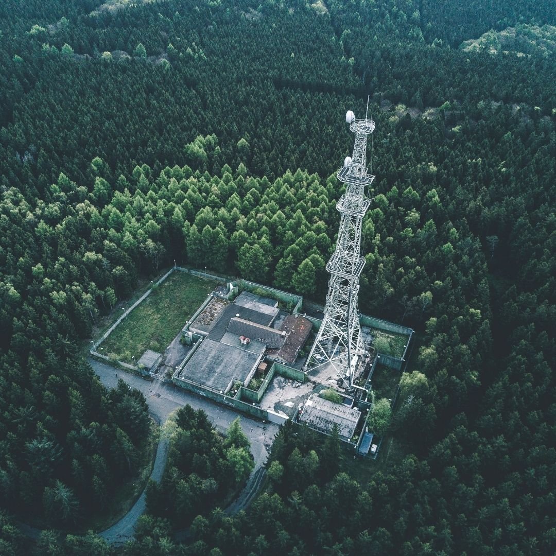 Aerial view of a communications tower rising above a forest